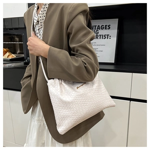 Dettaglio della borsa a tracolla in pelle bianca goffrata con logo dorato