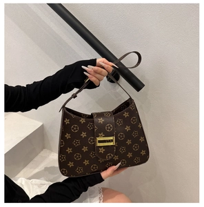 Detailed macro view of vintage brown bag featuring gold buckle and floral pattern