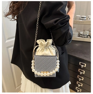 Detail of pearl handle, gold chain strap and geometric weave on bucket bag