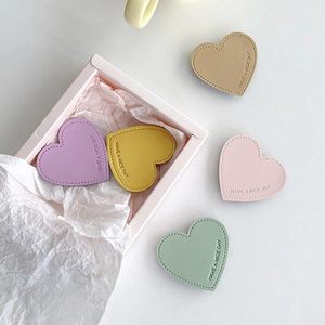 Close-up of heart-shaped leather phone grips with Have A Nice Day embossing and stitching