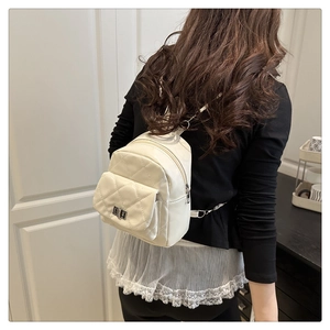 Back view of a woman wearing a white quilted mini backpack with silver metal clasp