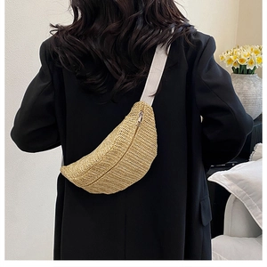 Detail of woven straw crossbody bag in beige with zipper and wide white shoulder strap