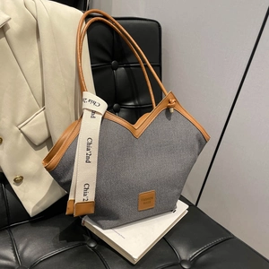 Retro grey canvas tote bag with brown leather trim on a stylish office setting