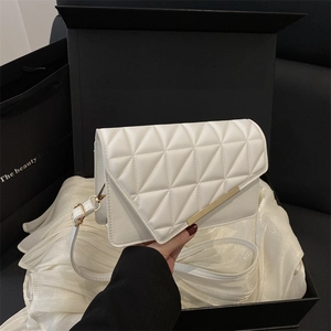 Elegant white quilted crossbody bag with gold metal trim on silk fabric backdrop