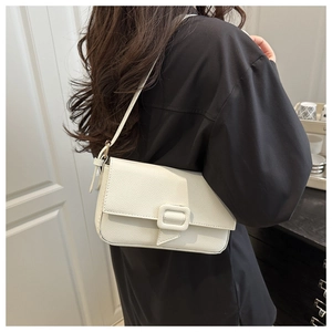Detailed view of creamy white baguette shoulder bag with leather buckle on model
