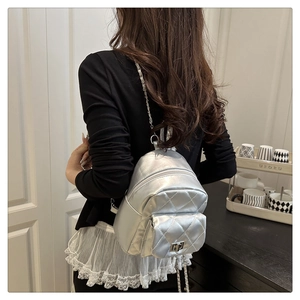 Silver quilted backpack with metallic finish and metal chain straps worn by model