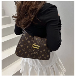 Detail view of brown shoulder bag with star pattern and gold rectangle buckle on model