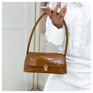 Close-up of brown patent leather baguette bag featuring a gold square metallic clasp