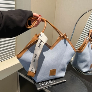 Blue canvas tote bag with brown leather trim and wide woven strap for daily commuting