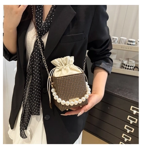 Detail of mini bucket bag featuring pearl handle and brown monogram pattern design
