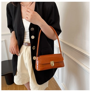 Detail of brown crocodile pattern leather handbag with elegant gold metal clasp