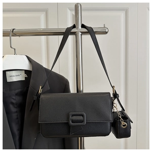 Detail of black pebbled leather baguette bag with matching mini pouch on metal chain