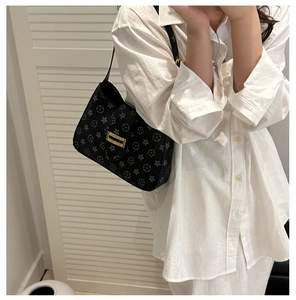 Close-up of stylish black underarm bag featuring grey star floral pattern and gold buckle