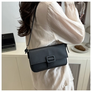 Detailed shot of black lychee grain leather baguette bag with square buckle closure