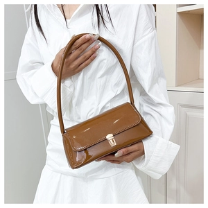 Detail of a brown glossy baguette bag featuring a gold rectangular metal buckle closure