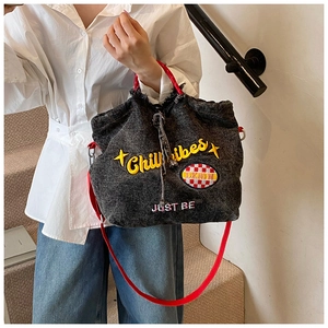 Detail of dark grey denim tote with Chili Vibes embroidery and red contrast handles