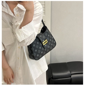 Mirror selfie showing a black underarm bag with star floral pattern and gold buckle