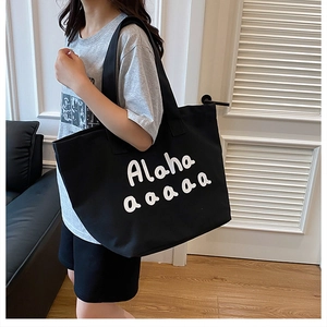 Detailed shot of spacious black canvas tote bag featuring white artistic lettering