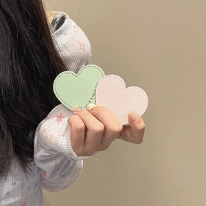 Detail of heart-shaped leather phone grips with stitched edges and stamped text