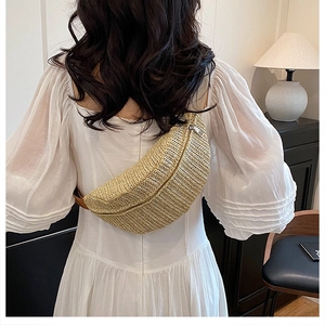 Detailed view of woven straw fanny pack with brown strap on a white dress