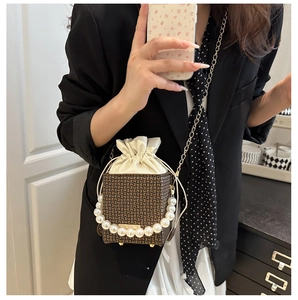 Detail of luxury box bag with pearl handle and monogram pattern on black blazer