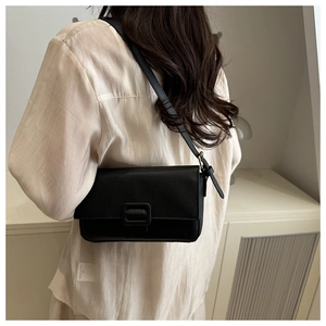 Close-up of black lychee grain leather crossbody bag with square buckle on model