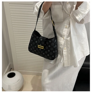 Detail of black underarm bag with vintage floral print and golden metal buckle