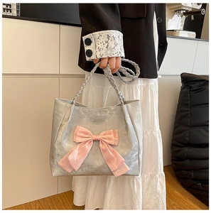 Detail of silver metallic tote bag with pink satin bow and braided shoulder straps