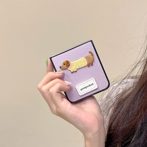 Detail of purple litchi leather case with embroidered dachshund and goodgoodluck tag