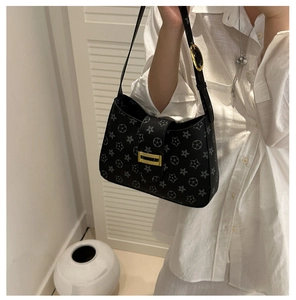 Detail of black printed underarm bag with gold hardware worn over a white shirt