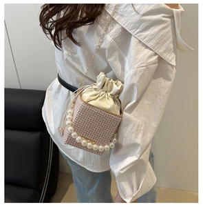 Detail of woven bucket bag with pearl handle, drawstring liner and gold chain strap