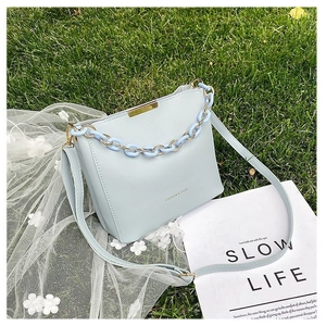 Close-up of light blue bucket bag with acrylic chain and gold metal trim on lace cloth
