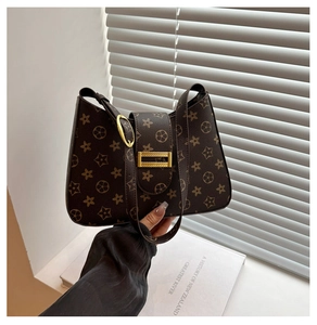 Close-up of brown floral print underarm bag with gold buckle on white shutter background