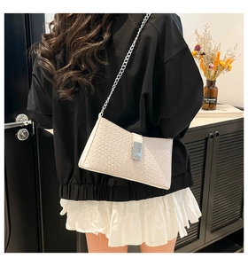 Close-up of white woven texture leather bag with silver chain strap and metal buckle