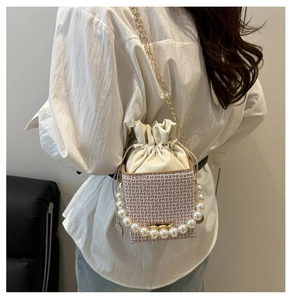 Detail showing the woven texture, pearl handle, and gold chain of this bucket bag