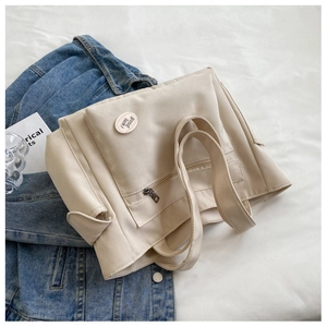 Detail of off-white canvas tote bag with front zipper pocket and good luck patch