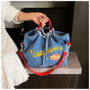 Detail of blue denim tote bag with red handles and yellow Chill Vibes embroidery