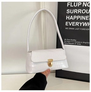 Detail of white crocodile pattern underarm bag featuring a stylish golden metal clasp