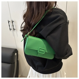 Close-up of green baguette bag in lychee texture leather worn over the shoulder
