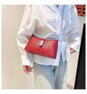 Detail of red woven texture PU leather handbag with metallic chain strap and buckle