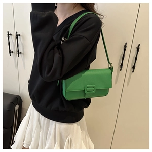 Close-up of green lychee pattern leather baguette bag with a front flap and buckle detail