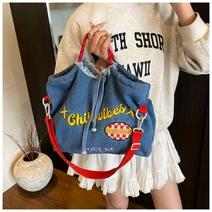 Detail of blue denim tote bag with red handles and Chilli vibes embroidery accents