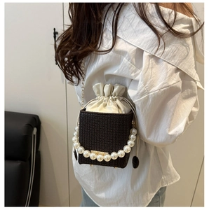 Detail of woven brown handbag with large pearl handle and drawstring cream liner bag