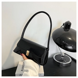 Detail of glossy black baguette bag featuring a polished gold buckle and sleek leather texture