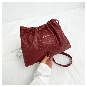 Dettaglio borsa in pelle intrecciata rosso scuro con coulisse e logo metallico