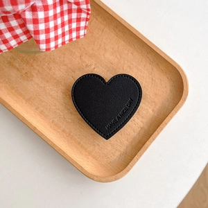 Macro detail of black leather heart phone grip with Have a Nice Day embossed text