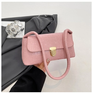 Detailed close-up of pink faux crocodile leather shoulder bag with golden metal twist lock