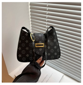 Detail of black patterned handbag featuring gold hardware and starry printed textured leather