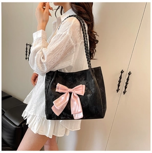 Detail of velvet tote bag with pink bow ribbon and woven strap for shoulder carry
