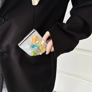 Detail of cute 3D bear and star charms on a transparent Z Flip case in a suit pocket